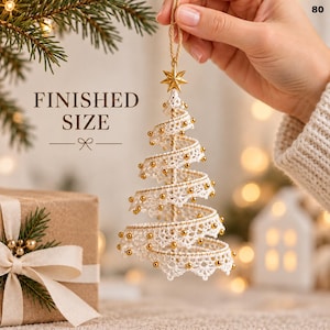May include: A spiral Christmas tree ornament crafted from white lace ribbon and small gold beads, topped with a gold star. The ornament hangs from a gold cord and features the text FINISHED SIZE 80 on the image background.