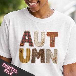 Peut inclure: Un t-shirt blanc avec le mot AUTUMN écrit en grandes lettres stylisées. Chaque lettre présente un motif unique, incluant un tartan rouge et noir, des pois beiges, des rayures brunes et des illustrations florales avec des glands et du blé.