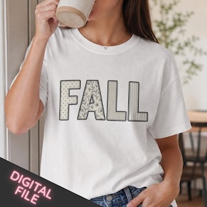 Peut inclure: Un t-shirt blanc à manches courtes avec le mot FALL écrit en grandes lettres majuscules. Chaque lettre présente un motif distinct : le F est à pois, le A a un motif floral, le premier L est à carreaux et le second L a des rayures verticales.
