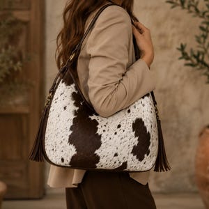 Close-up of woman wearing women's woven cowhide leather crossbody hobo bag paired with beige blazer and brown trousers