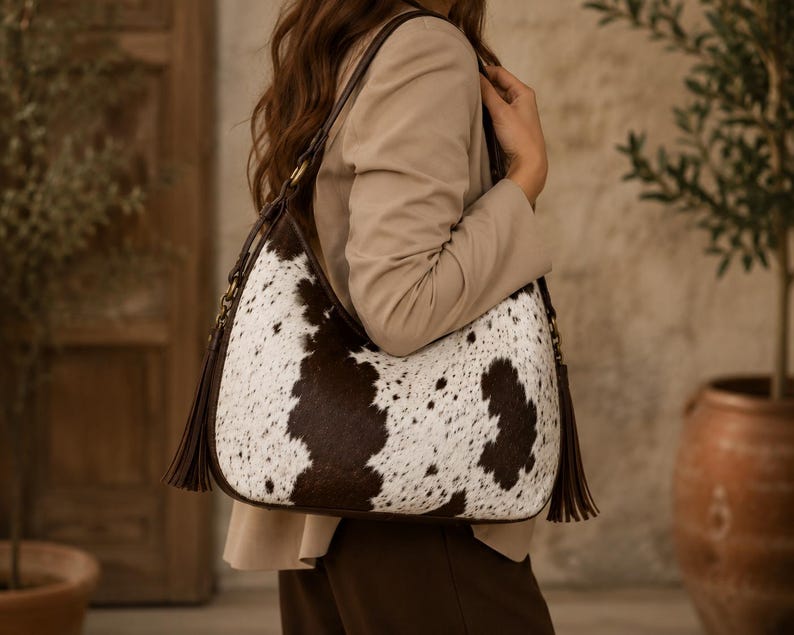 Close-up of woman wearing women's woven cowhide leather crossbody hobo bag paired with beige blazer and brown trousers