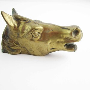May include: A gold-colored metal horse head sculpture. The horse's mouth is open and its eyes are detailed.