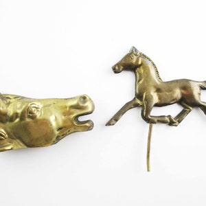 May include: Two gold-colored metal horse figurines. One is a horse head and the other is a running horse.