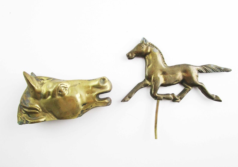 May include: Two gold-colored metal horse figurines. One is a horse head and the other is a running horse.