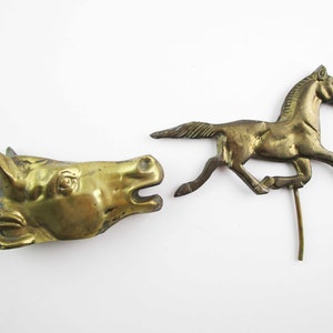 May include: Two brass horse figurines. One is a full-bodied horse running, the other is a horse head.