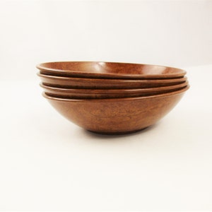 May include: A stack of four brown bowls with a speckled pattern. The bowls have a smooth, glossy finish and a simple, rounded design. The bowls are stacked on top of each other, with the rims visible.