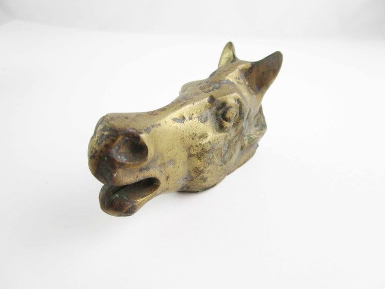 May include: A brass horse head sculpture with a distressed finish. The horse's head is tilted to the side, and its mouth is slightly open.