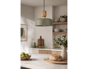 May include: A dome-shaped pendant light fixture featuring a matte olive green metal shade, a cylindrical light-toned wooden accent piece at the top, and a gold-colored metal connector, suspended by a thin black cord from the ceiling.