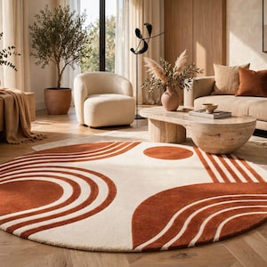 May include: A large circular area rug featuring a cream-colored base with bold, burnt orange geometric patterns. The design consists of concentric semi-circles, curved lines, and solid circles arranged in a repeating, symmetrical layout.