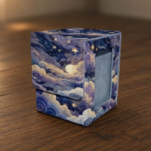May include: A square deck box featuring a vibrant night sky print with swirling purple and blue clouds, a glowing yellow moon, and scattered stars. The box has a textured exterior, a hinged lid, and a rectangular cutout on the side.