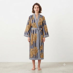 May include: A long-sleeved robe featuring a pattern of orange and black tigers overlaid on a background of vertical grey and white stripes. The garment includes a matching fabric tie belt at the waist and a wide collar with striped trim.
