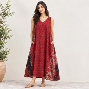 Puede incluir: Un vestido sin mangas hasta los tobillos en un tono rojo intenso con un patrón negro denso e intrincado. La prenda tiene cuello en V, una silueta en forma de A relajada y bolsillos laterales, con paneles florales en negro y gris.