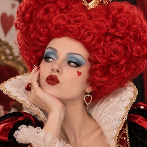 May include: A gold crown with a central red heart, a voluminous red curly wig, a gold ring with a red heart-shaped stone, and gold heart-shaped earrings with red stones. The attire includes a high white lace collar and a red and black dress.