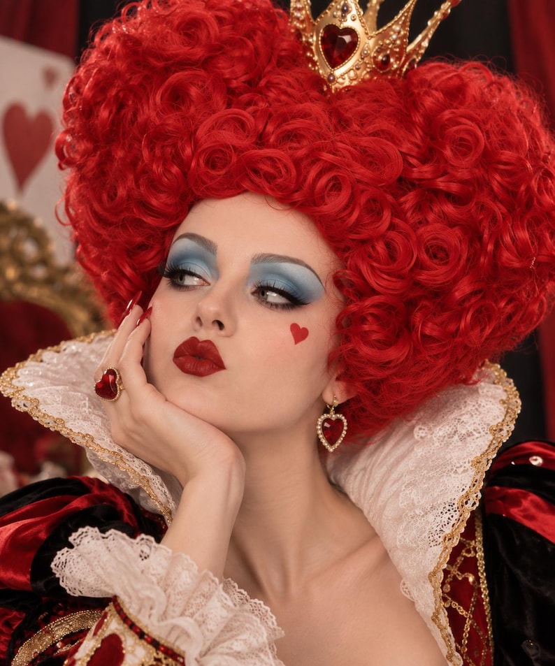 May include: A gold crown with a central red heart, a voluminous red curly wig, a gold ring with a red heart-shaped stone, and gold heart-shaped earrings with red stones. The attire includes a high white lace collar and a red and black dress.
