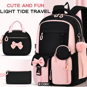 Può includere: Un set zaino nero e rosa chiaro con borsa per il pranzo e astuccio abbinati. Lo zaino presenta scomparti multipli con cerniera, un fiocco rosa, una tasca rotonda e un pon-pon. Il testo riporta CUTE AND FUN LIGHT TIDE TRAVEL.