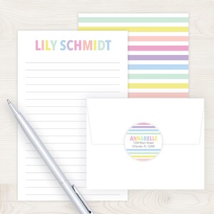a variety of colorful stationery items, including a blank lined paper, a pen, and an envelope with a label.