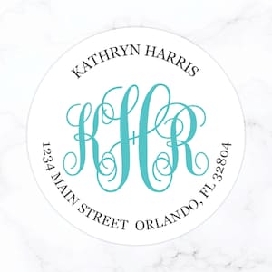 May include: White round sticker with black text that reads "Kathryn Harris" and "1234 Main Street Orlando, FL 32804". A turquoise monogram "KHR" is in the center of the sticker.