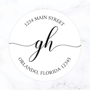 May include: A white round return address label with black text. The text reads "1234 Main Street, Orlando, Florida 12345" and features the initials "gh" in a cursive font.