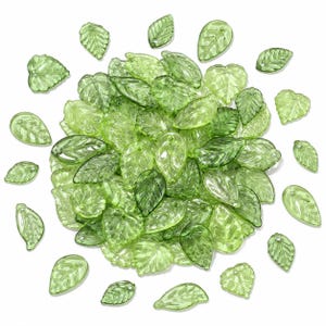 May include: A collection of translucent light green leaf-shaped beads made of glass or acrylic. Each bead features a detailed embossed vein pattern and a small hole at the top for stringing. The beads are arranged in a circular cluster.