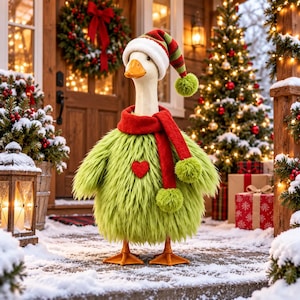 May include: A white goose wearing a green shaggy sweater with a red heart, a red scarf with pom-poms, and a red and green striped Santa hat. The goose stands on a snowy porch decorated with a Christmas wreath, a lit tree, and wrapped gifts.