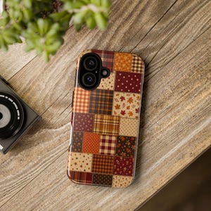 Puede incluir: Una funda para smartphone con un diseño de patchwork de varios patrones con temática otoñal, incluyendo cuadros, vichy, pequeños estampados florales, estrellas y hojas de arce en tonos marrón, naranja, rojo, crema y amarillo con recorte de cámara.