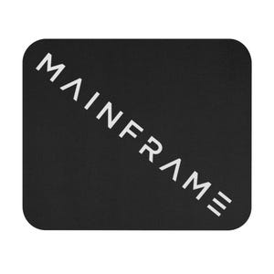 Puede incluir: Una alfombrilla de ratón rectangular negra con esquinas redondeadas que presenta la palabra MAINFRAME impresa en una fuente blanca, negrita y sin remates. El texto está orientado en diagonal desde la esquina inferior izquierda a la superior.