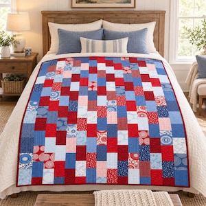 May include: A patchwork quilt featuring a rectangular grid pattern in shades of red, white, and blue. The quilt is composed of various fabric squares and rectangles with solid colors, stripes, and circular patterns, finished with a red border.