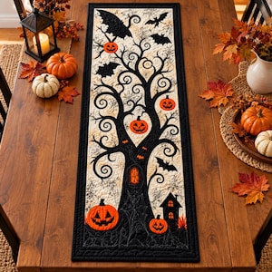 Peut inclure: Un chemin de table rectangulaire en tissu présentant une silhouette d'arbre noir matelassé sur un fond crème. Le motif comprend des citrouilles orange suspendues aux branches, une silhouette de maison noire et des chauves-souris noires.