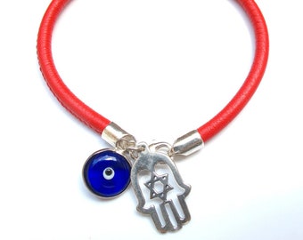 May include: Red leather bracelet with a silver charm featuring a Hamsa hand with a Star of David and a blue evil eye charm.
