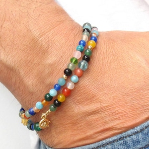 Pode incluir: Um bracelete de contas multicoloridas com um fecho de ouro. O bracelete &eacute; feito com uma variedade de pedras, incluindo azul, verde, vermelho e laranja.