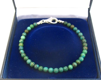 May include: A turquoise gemstone bracelet with a silver clasp, displayed in a blue velvet box.