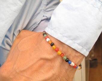 May include: A multi-colored beaded bracelet with silver and black beads. The bracelet is made of various gemstones, including red, orange, yellow, green, and blue.