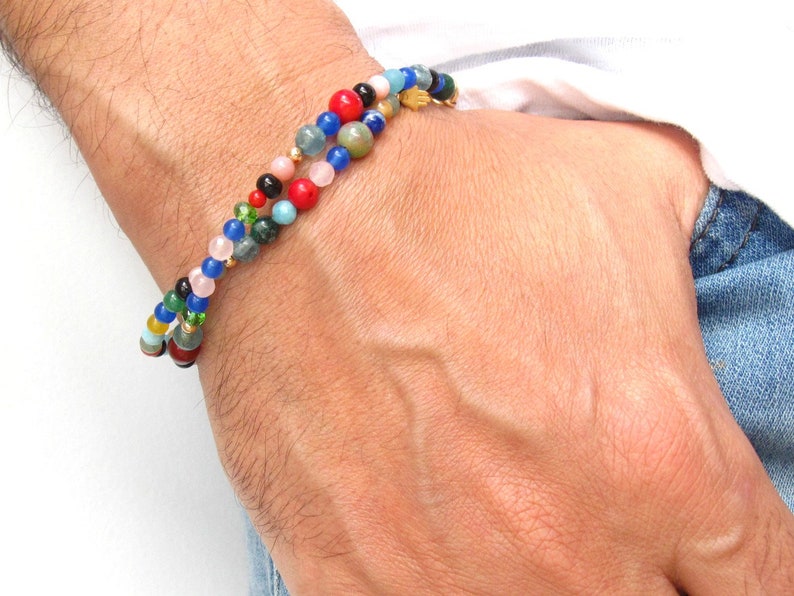 Pode incluir: Um bracelete de contas multicoloridas com um fecho dourado. O bracelete &eacute; feito com v&aacute;rias pedras, incluindo vermelho, azul, verde e rosa.
