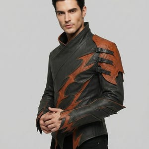 May include: A black and brown jacket featuring a high collar, asymmetrical layered panels, and jagged edges. The left shoulder is accented with a brown leather panel secured by three black buckled straps, while the sleeves have matching jagged cuffs.