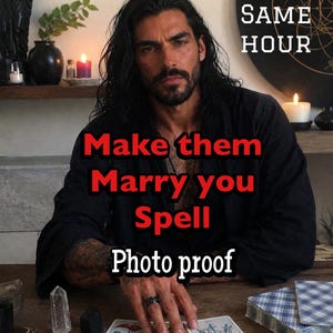 Może przedstawiać: Osoba z długimi ciemnymi włosami w czarnej szacie siedzi przy drewnianym stole z kartami tarota. Tekst na obrazku: SAME HOUR, Make them Marry you Spell, Photo proof. Przezroczysty kryształ i czarny kamień znajdują się obok kart na stole.