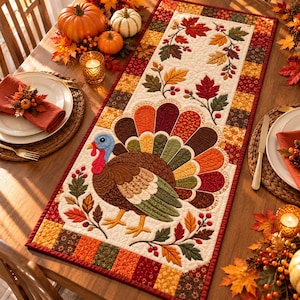 May include: A rectangular quilted table runner featuring a central appliqué of a turkey with a multi-coloured fan-shaped tail, surrounded by embroidered autumn leaves and berries, bordered by a patchwork pattern of orange, red, and brown squares.
