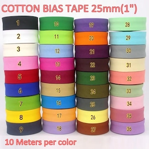 May include: A collection of 36 rolls of cotton bias tape, each 25mm (1 inch) wide and 10 meters long. The rolls are arranged in four vertical columns, each labeled with a number from 1 to 36, displaying a wide variety of solid colors.