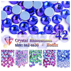 May include: A collection of round, faceted blue crystal rhinestones with flat, opaque backings. The image includes text reading Crystal Rhinestones, size: ss2-ss30, Hotfix, and the number 42, alongside smaller panels showing pink, purple, green, and blue stones.