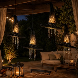 May include: Four black witch hats suspended in the air, each featuring a pointed crown and wide brim. The hats are illuminated from within by warm glowing string lights, with additional delicate light strands hanging down from the brims.