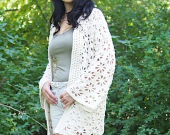 May include: A white crochet cardigan with a lacy pattern. The cardigan has a relaxed fit and long sleeves.