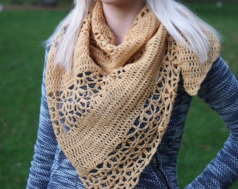 May include: A crocheted shawl in a mustard yellow color. The shawl is triangular in shape and has a delicate lace pattern.