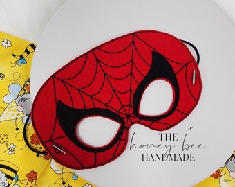 May include: Red felt Spiderman mask with black eye holes and a web design. The mask has a black elastic band for wearing. The mask is labeled "THE honey bee HANDMADE".