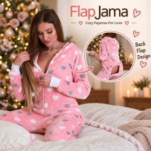 May include: A pink hooded one-piece pajama with a white and grey heart pattern, featuring a front zipper, white cuffs, and a rear flap design. The text FlapJama Cozy Pajamas For Love and Back Flap Design is visible on the image.