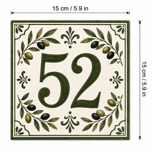 May include: A square ceramic house number tile featuring the number 52 in dark green. The design includes olive branches with black and green olives on a cream background, framed by a dark green border. It measures 5.9 inches by 5.9 inches.