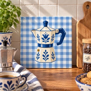 Könnte beinhalten: Ein quadratisches Wandbild mit einer zentralen Illustration einer cremefarbenen Mokkakanne mit blauen Blumenmustern und einem blauen Griff vor einem hellblau-weiß karierten Hintergrund. Das Design ist klar, grafisch und mittig platziert.