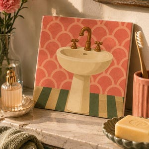 May include: A square decorative tile featuring a centred illustration of a cream-coloured pedestal sink with a brass-toned faucet and handles. The background displays a pink scalloped pattern above a floor with alternating green and beige stripes.