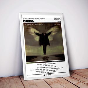 May include: A framed poster featuring the Breaking Benjamin album Phobia, released August 8, 2006. The artwork displays a dark figure with large wings, a tracklist with song titles and durations, and a Spotify-style code at the bottom.