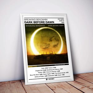May include: A framed poster featuring the Breaking Benjamin album Dark Before Dawn. The artwork displays a solar eclipse over a dark landscape. Below the image, a tracklist includes song titles and durations, with a Spotify code at the bottom.