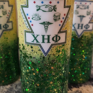 May include: A yellow and green glitter tumbler with a white logo that says "Founded 1932" and "XHF". The logo also features a medical caduceus, a lotus flower, a handshake, and an open book.