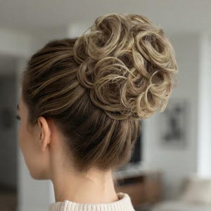 May include: A hair extension styled as a voluminous, curly high bun. The hairpiece features a blend of light blonde and darker brown tones, creating a multi-dimensional effect. The curls are tightly coiled and arranged in a circular, full shape.